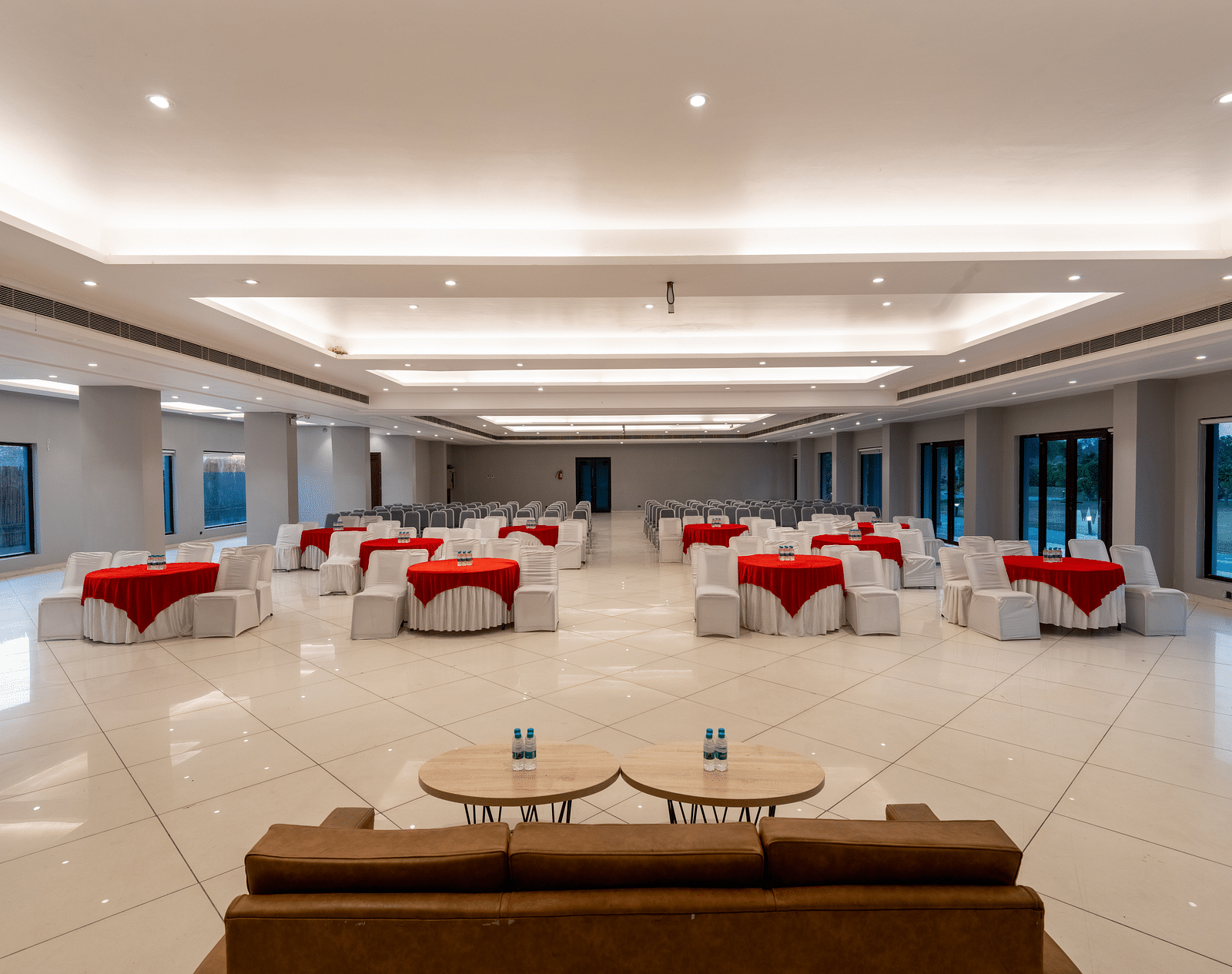 Tables with neatly decorated tablecloths, a plush sofa, and two round tables set in front at DLS Forest Vines Resort.